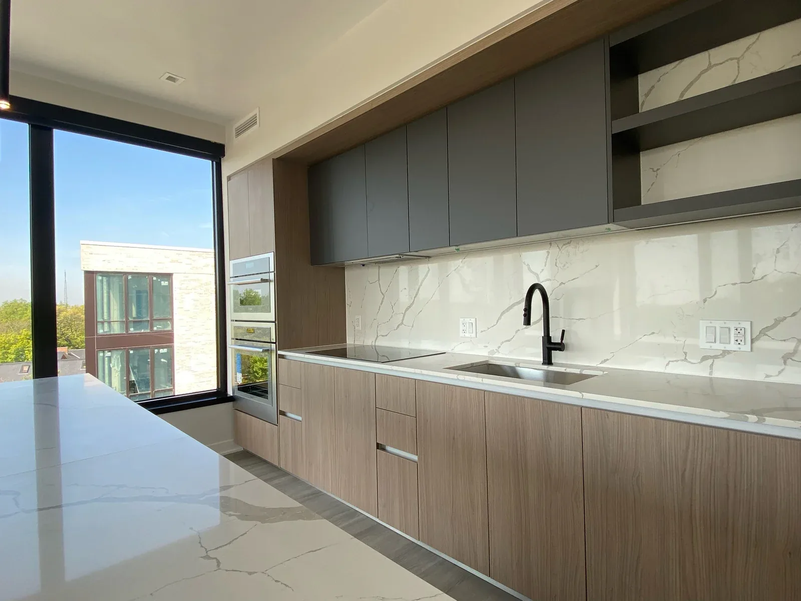 Finished modern kitchen with a white veined stone island and backsplash